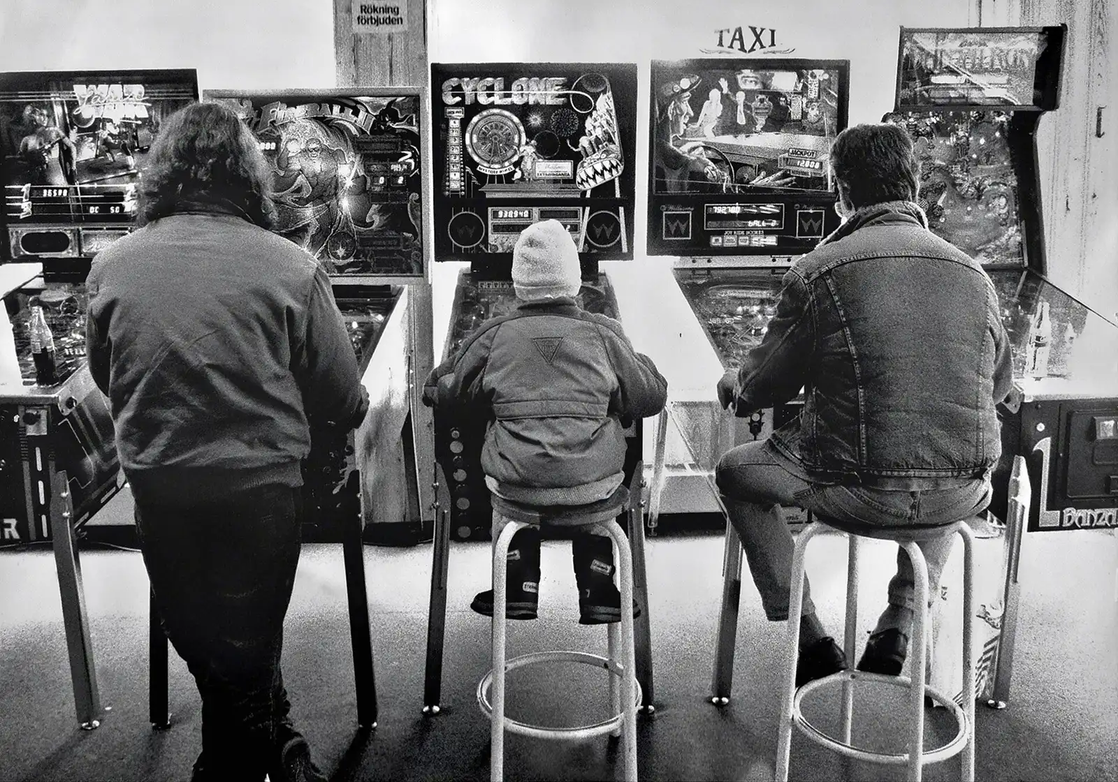 Spieler jeden Alters an Flipperautomaten in einer Spielhalle 1989